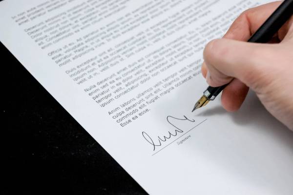 Man's hand signing a contract at Gallo Uwalaka law firm in Houston